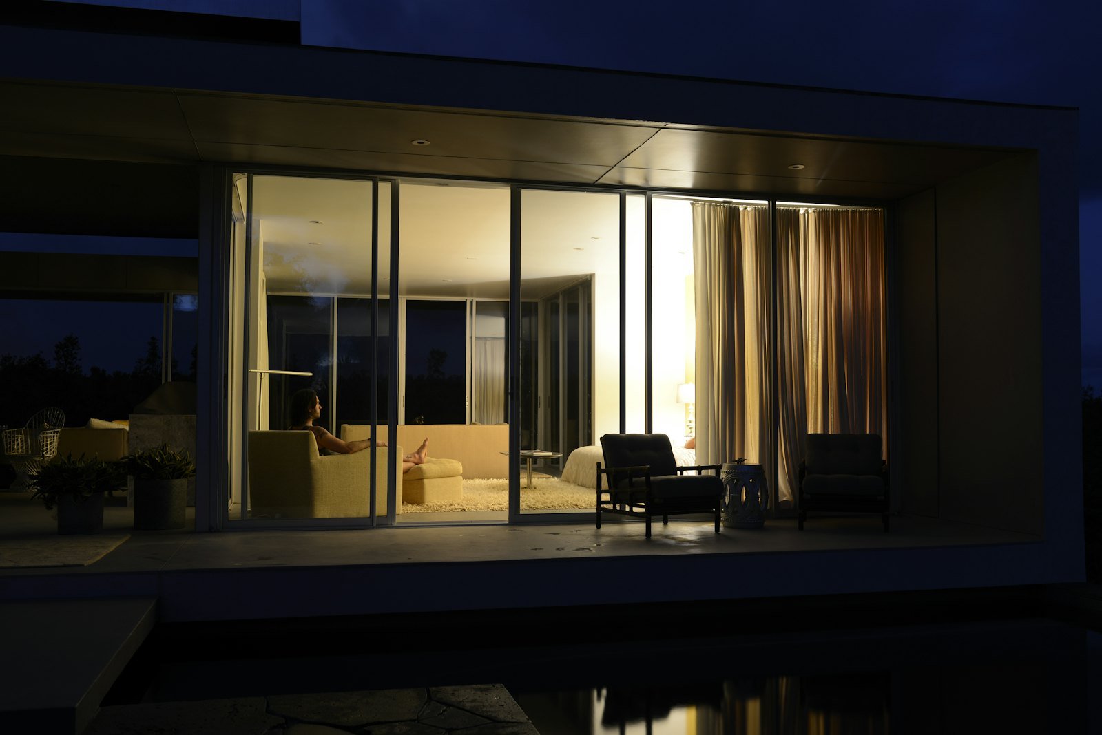 Modern villa glowing at night while the owner relaxes inside